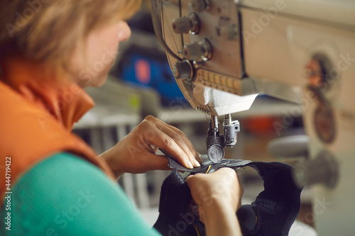 Foto Shoemaker sewing leather and velcro for making or repairing shoe using professional equipment