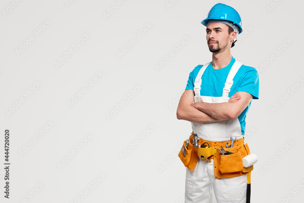 Confident builder in uniform with toolkit Confident builder in uniform with toolkit
