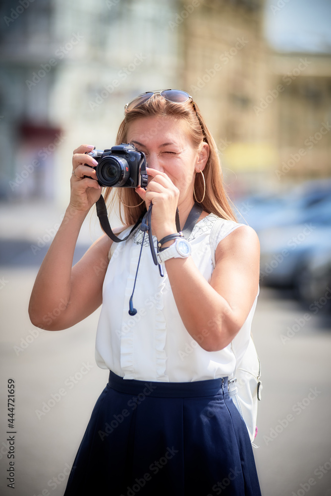 Young woman takes snapshot with a digital camera on the city street
