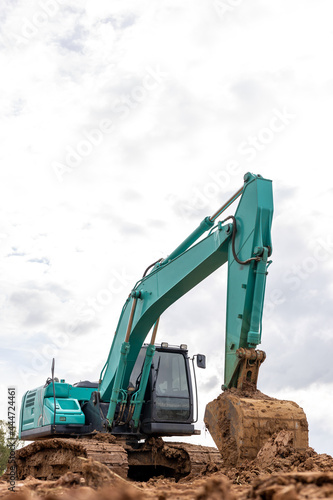 A muddy green backhoe parked on the ground.