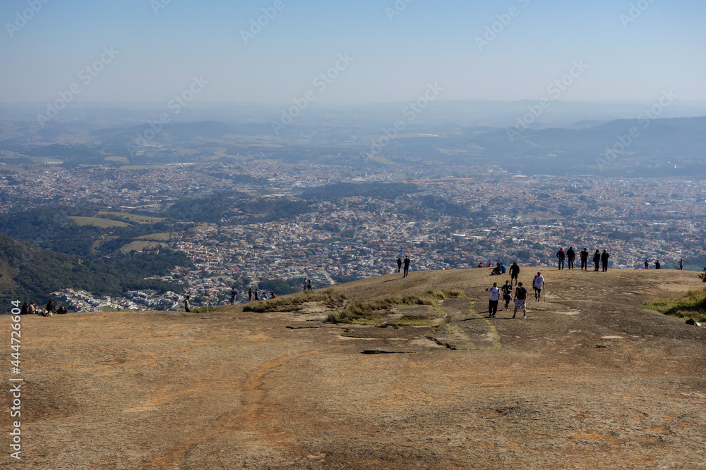 tourists admiring the panoramic view from the peak of rock formation. cityscape, mountaineering, climb up