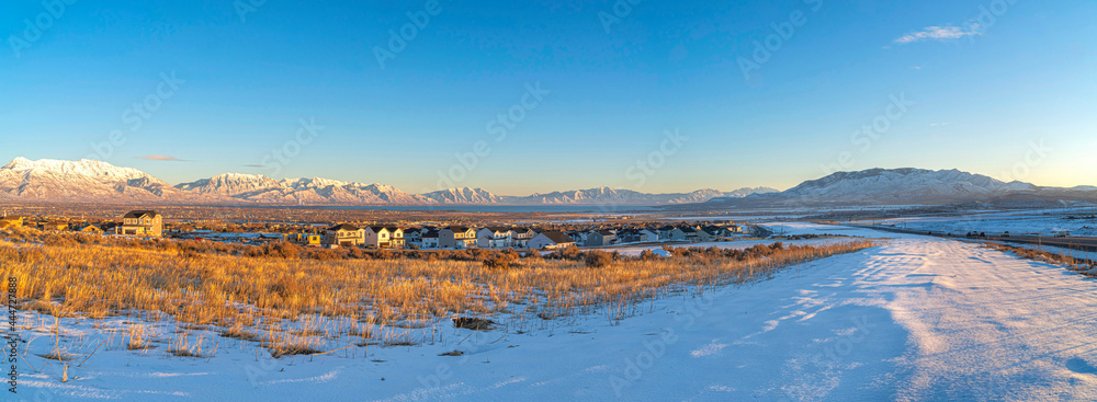 Naklejka premium Vast field of snow with large houses at Saratoga Springs, Utah with view of Wasatch Mountains