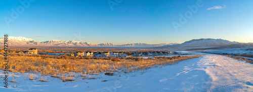 Vast field of snow with large houses at Saratoga Springs, Utah with view of Wasatch Mountains