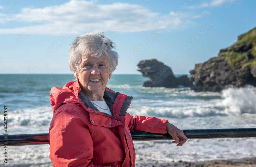 Happy senior woman on beach in red coat Happy senior woman on beach in red coat