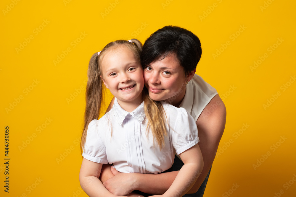 Happy woman, have fun with cute child baby girl 6-7 years old Mommy little kid daughter stand behind hug, isolated on yellow background. Mother's Day love family concept. Happy woman, have fun with cute child baby girl 6-7 years old Mommy little kid daughter stand behind hug, isolated on yellow background. Mother's Day love family concept.