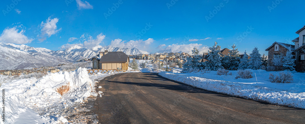 Snowy town with houses at Draper, Utah with snow plowed road and a view of Wasatch mountains