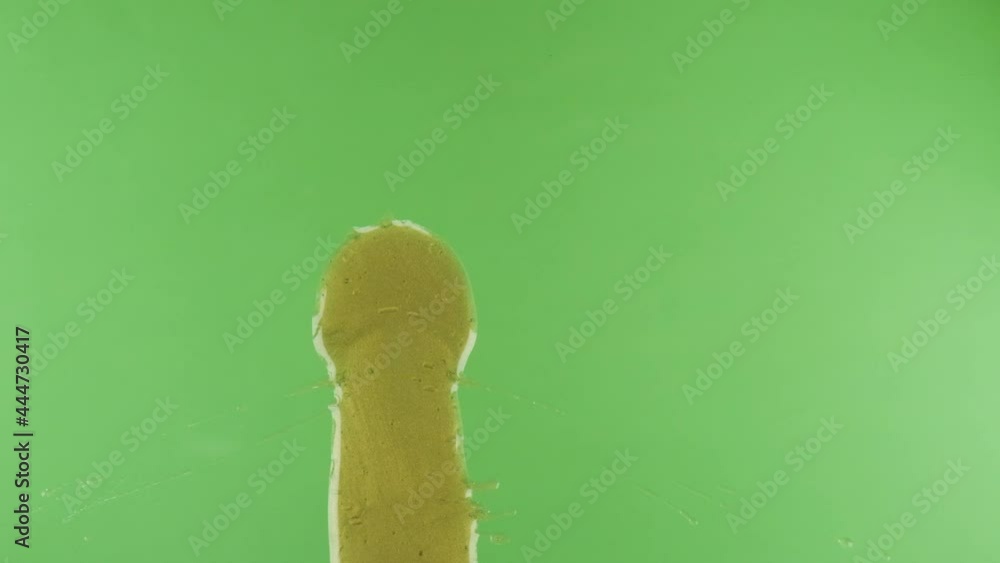 Slow motion. A spot of gold paint falls on a green background. Chic golden background. Pouring golden liquid over green background. Luxury background. Top view Slow motion. A spot of gold paint falls on a green background. Chic golden background. Pouring golden liquid over green background. Luxury background. Top view