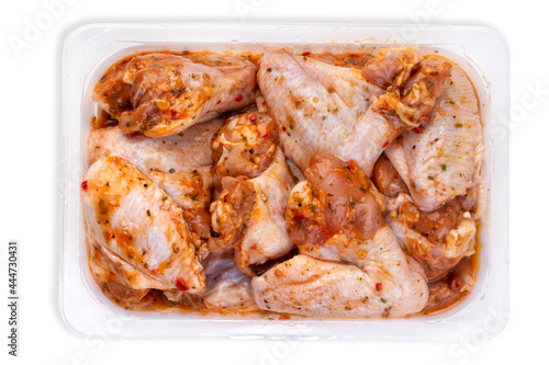 Raw spicy chicken wings for grilling in a transparent plastic box photo