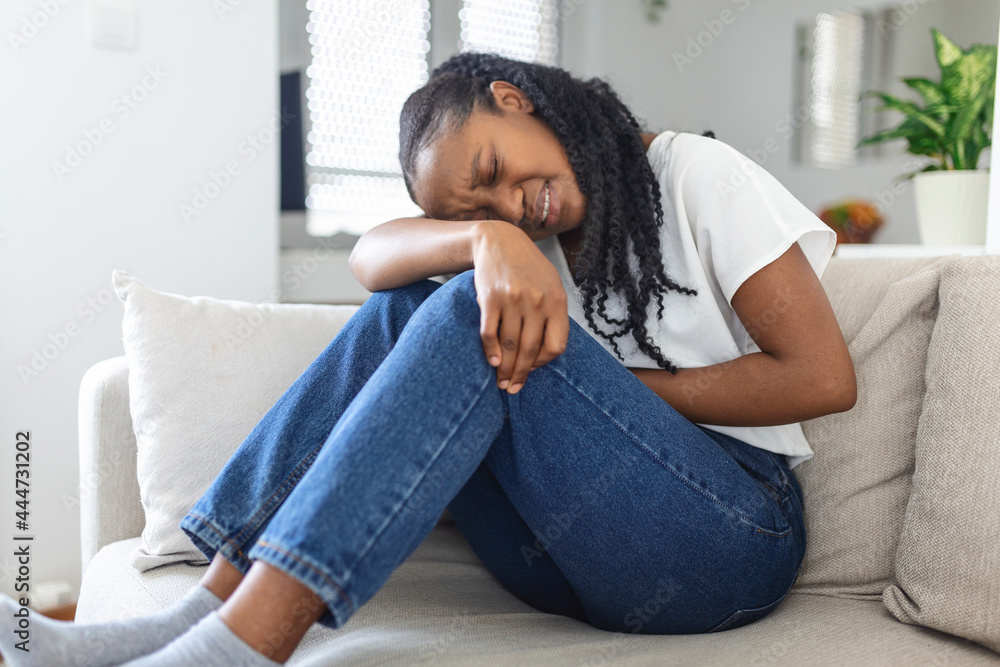 Woman in painful expression holding hands against belly suffering menstrual period pain, lying sad on home bed, having tummy cramp in female health concept Woman in painful expression holding hands against belly suffering menstrual period pain, lying sad on home bed, having tummy cramp in female health concept