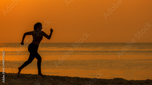 Silhouette athletic woman jogging exercise and relax and freedom on sand beach. People running and workout in sunset background. Lifestyle and Healthy Concept.