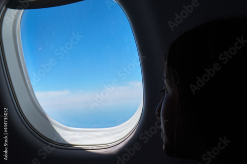 Young man looking out the window of an airplane at the clouds.