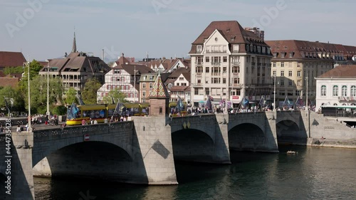 basel switzerland, 24 april. 2021: rhine bridge basel, filmed from the old town, yellow and green streetcar crossing the bridge, many people are out in the city in the afternoon