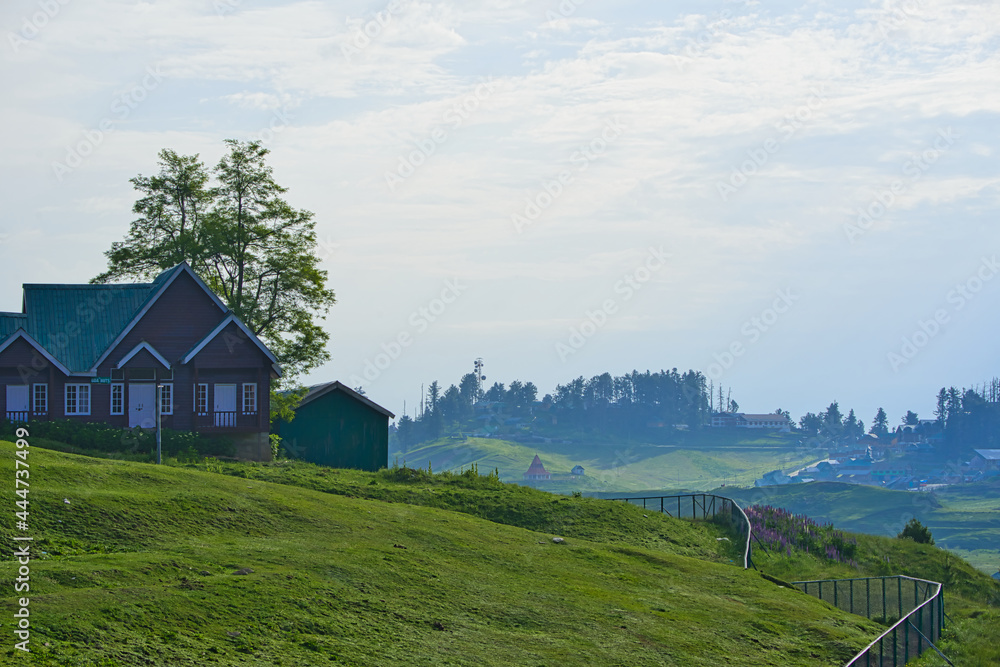 Obraz premium Morning view of a farm on the hills of Gulmarg. Fog surrounds and many houses, Jammu and Kashmir, India. June 2018.