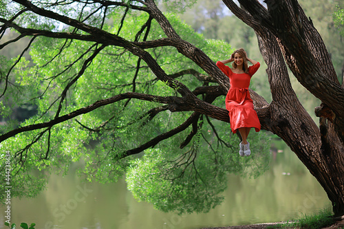 springtime dreaming female girl sitting on a tree branch, spring forest park photo
