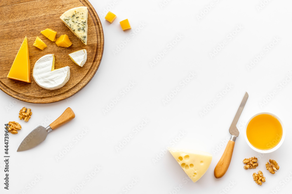 Set of cheese on wooden board with cheese knives, top view