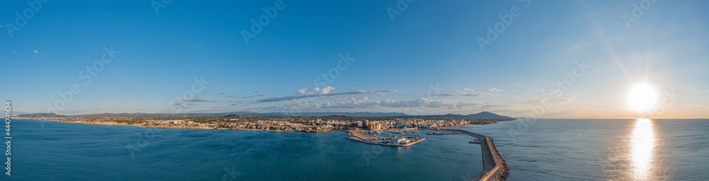 Drone panorama of the Spanish town of Vinaros with the large breakwater at the entrance to the port during sunrise