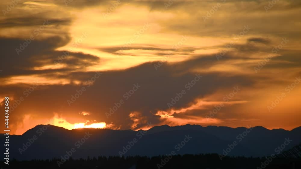 Time lapse of beautiful colorful sunset with dramatic sky. Silhouette of Alps in the distance. Real time view of clouds moving in the sky. Orange golden hour color. Static shot Time lapse of beautiful colorful sunset with dramatic sky. Silhouette of Alps in the distance. Real time view of clouds moving in the sky. Orange golden hour color. Static shot