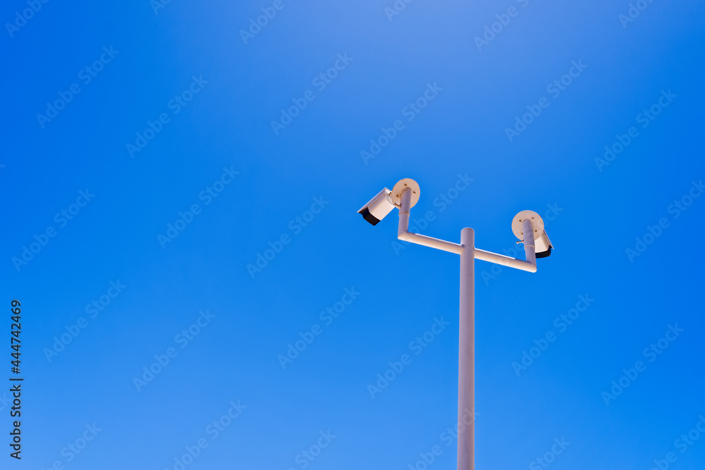 Digital CCTV cameras are located on a metal pole against the backdrop of a clear sky. The concept of security, protection of private property, video surveillance. Digital CCTV cameras are located on a metal pole against the backdrop of a clear sky. The concept of security, protection of private property, video surveillance.