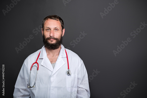 Exhausted Caucasian American doctor in a dark room. Bad Medicine. adult bearded man wearing doctor uniform and stethoscope looking sleepy and tired, exhausted for fatigue, lazy eyes in the morning