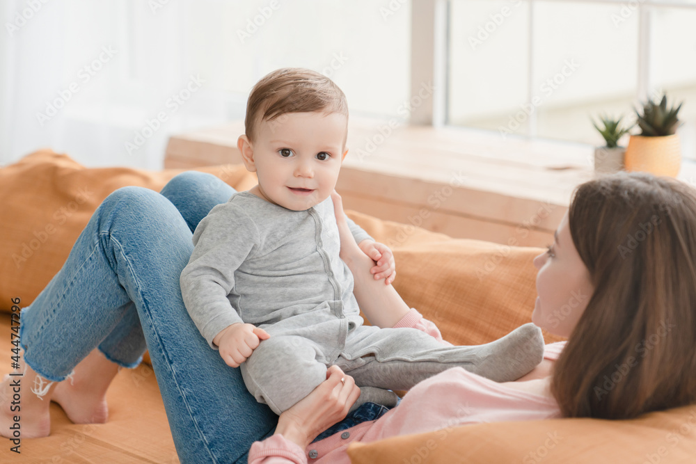 Cute lovely small kid infant newborn baby sitting on mother`s lap. Young mother nanny babysitter spending time with baby child at home on lockdown. Motherhood and adoption concept Cute lovely small kid infant newborn baby sitting on mother`s lap. Young mother nanny babysitter spending time with baby child at home on lockdown. Motherhood and adoption concept