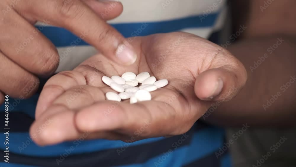 man's hand with medicine spilled out of the pill container man's hand with medicine spilled out of the pill container