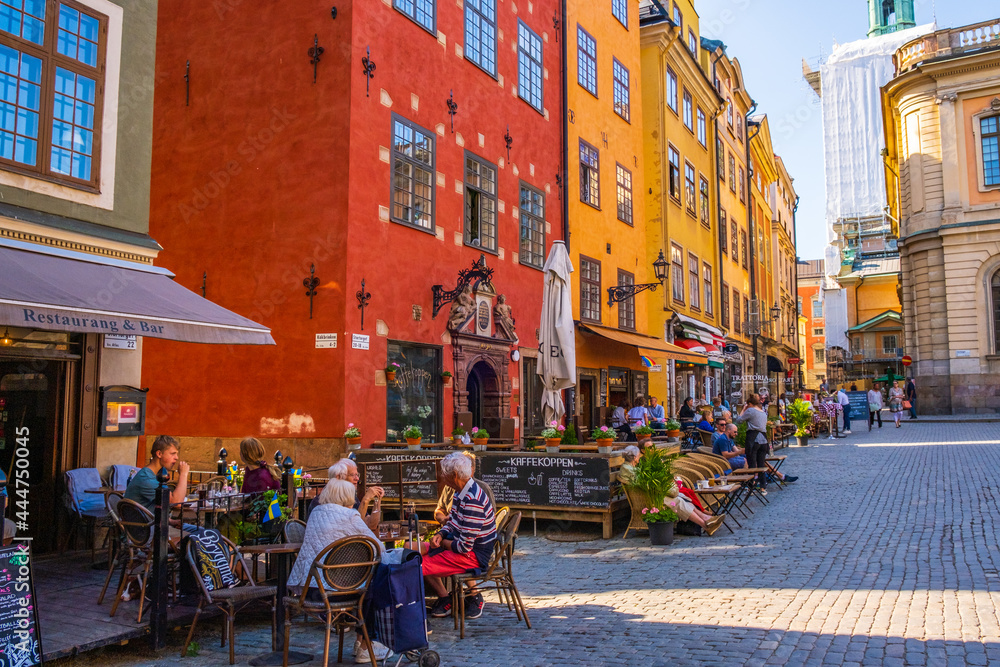 Stockholm Sweden - July 1 2021: Colourful historic buildings and houses in Gamla Stan, Main S. Romantic medieval city centre alleys. Popular tourist destination in Scandinavia on a sunny day. - obrazy, fototapety, plakaty 