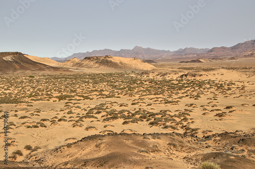 sand dunes with grass in front of distant mountain range, stunning african landscape, savanna