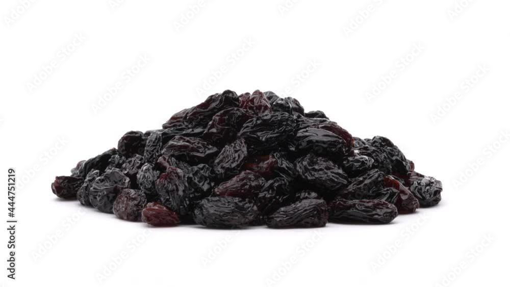 Close-up of dark sultana raisins pile rotating on the turntable. Isolated on white background. Close-up of dark sultana raisins pile rotating on the turntable. Isolated on white background.