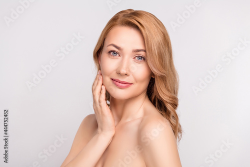 Photo portrait woman after shower smiling with nude shoulders applying cream on cheeks isolated white color background copyspace