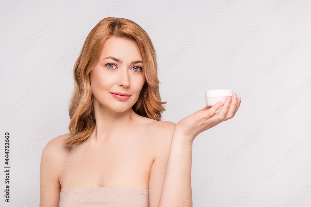 Portrait of attractive healthy woman holding on palm moisturizing cream advert isolated over grey pastel color background Portrait of attractive healthy woman holding on palm moisturizing cream advert isolated over grey pastel color background