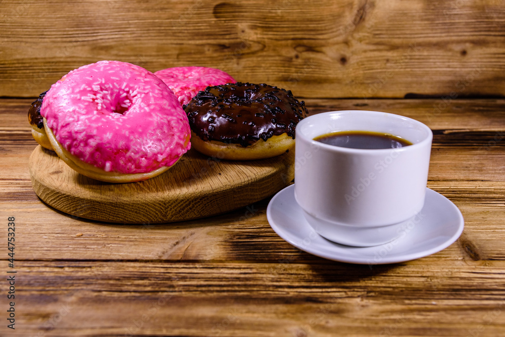 Cutting board with glazed donuts and cup of coffee on a wooden table