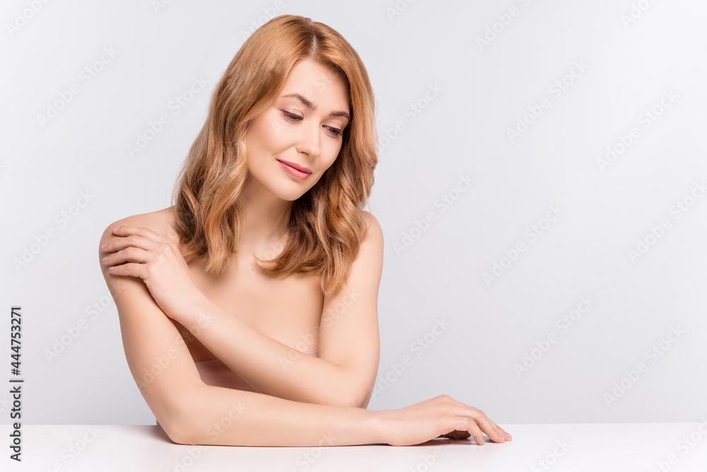 Portrait of attractive healthy woman sitting touching shoulder copy space ad isolated over grey pastel color background Portrait of attractive healthy woman sitting touching shoulder copy space ad isolated over grey pastel color background