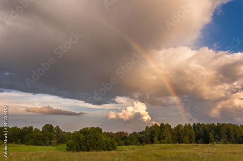 Rainbow over stormy sky. Rural landscape with rainbow over dark stormy sky in a countryside at summer day.