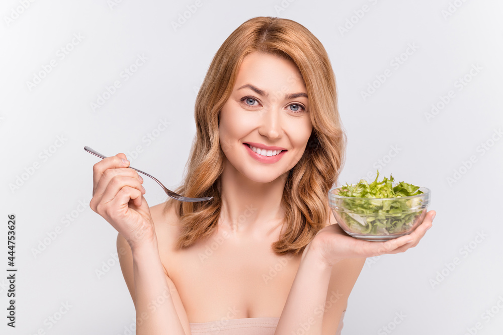 Portrait of attractive cheerful woman eating tasty salad vegs fit life style isolated over grey pastel color background