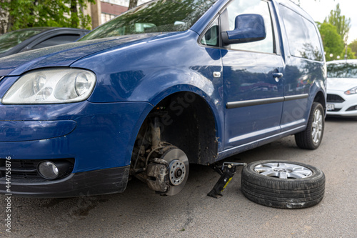 A broken wheel is standing next to the car. © puhimec