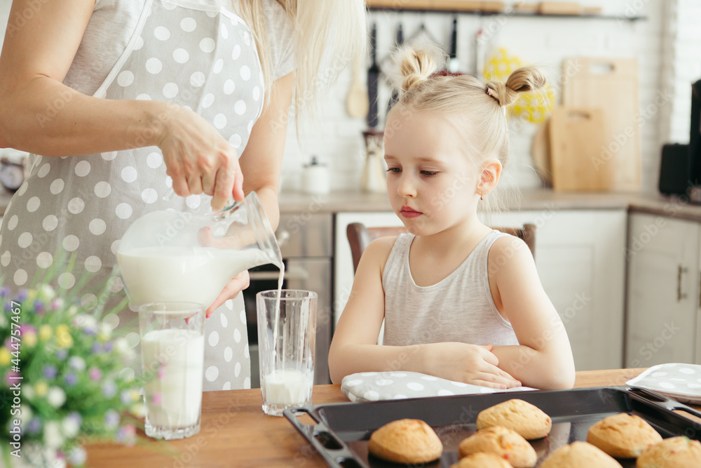 Cute little girl and mom eating freshly baked cookies with milk Cute little girl and mom eating freshly baked cookies with milk