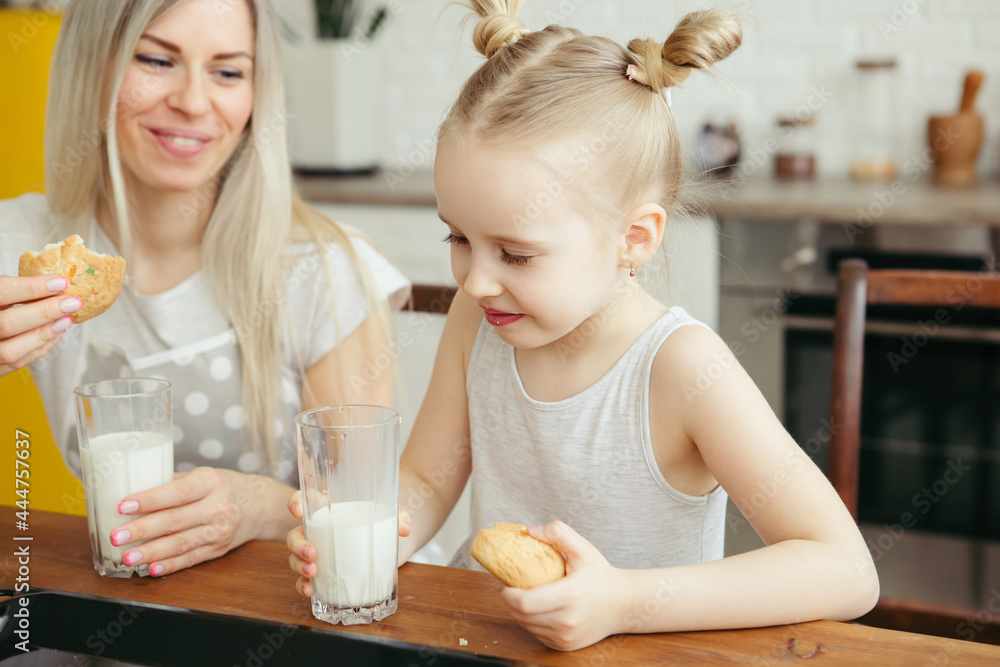 Cute little girl and mom eating freshly baked cookies with milk Cute little girl and mom eating freshly baked cookies with milk