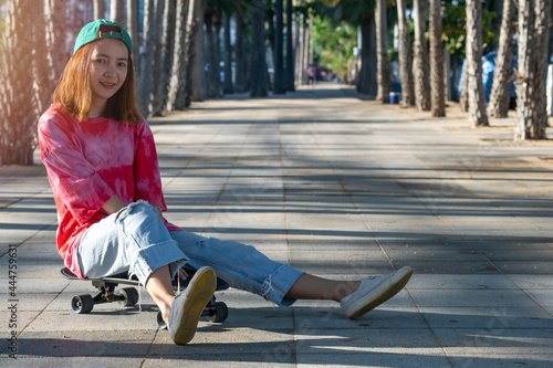 woman teennager wearing sportwear and shoes playing,sitting on surf skate on the road oudoor in the morning. Relax and enjoy extreme surfskate on summer holiday at the beach.