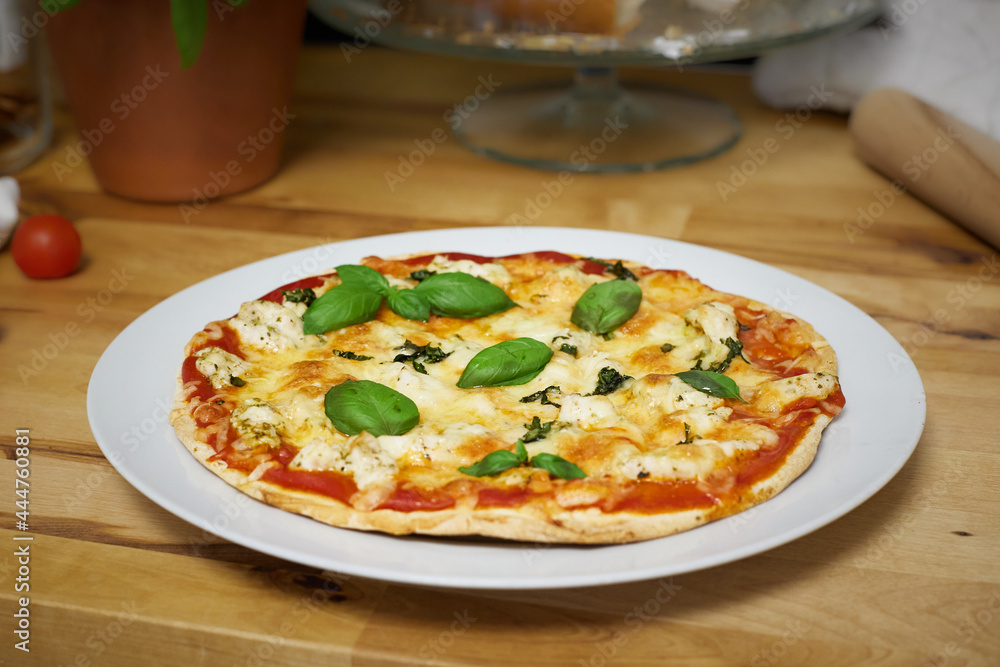 Homemade artisan pizza on white plate on wooden counter top Homemade artisan pizza on white plate on wooden counter top