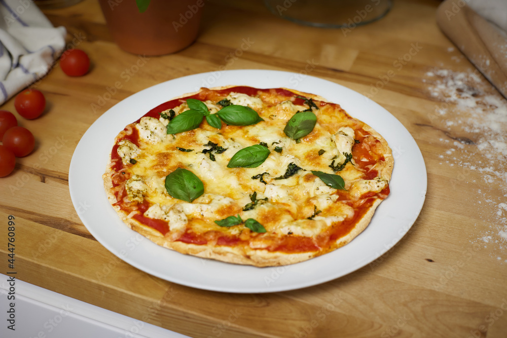 Homemade artisan pizza on white plate on wooden counter top Homemade artisan pizza on white plate on wooden counter top