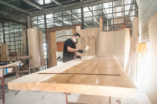 Foto Man in respirator mask painting wooden planks at workshop