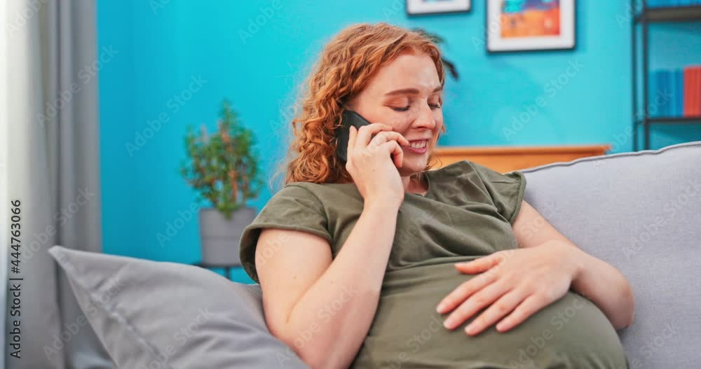 A girl in advanced pregnancy sits on the couch and relaxes, talks on the phone with her parents, friends, tells about her well-being, about the baby and its movements, they plan shopping for a newborn A girl in advanced pregnancy sits on the couch and relaxes, talks on the phone with her parents, friends, tells about her well-being, about the baby and its movements, they plan shopping for a newborn