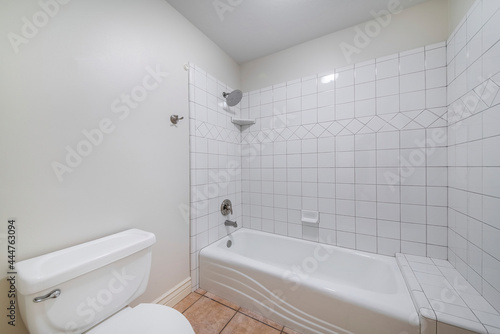 Fototapeta Interior of a bathroom with toilet bowl and alcove bathtub shower combo with til