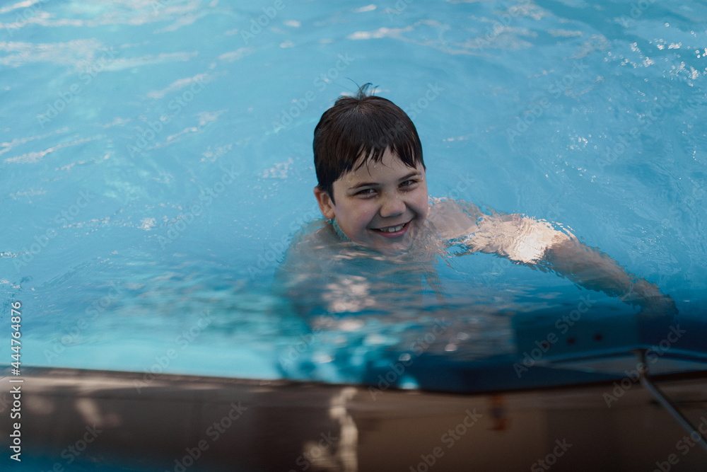 A happy child is sitting in the blue water on a sunny day.
