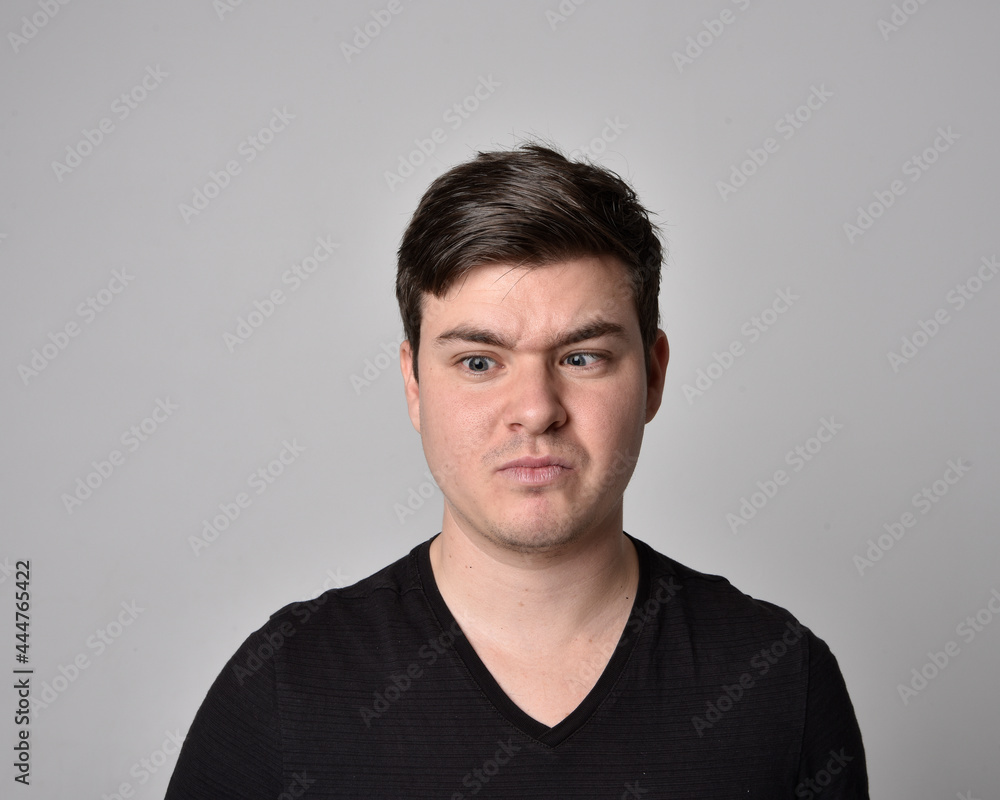 Obraz premium Close up head and shoulders portrait of a brunette. young man with a variety of expressive facial expressions. Isolated on a light grey studio background.