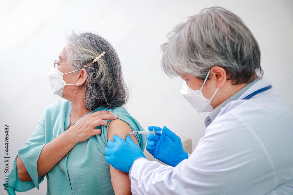 Fototapeta premium Close-up portrait of an elderly woman receiving coronavirus vaccination from a male doctor wearing blue gloves To strengthen the immune system to prevent infection. Elderly Vaccination