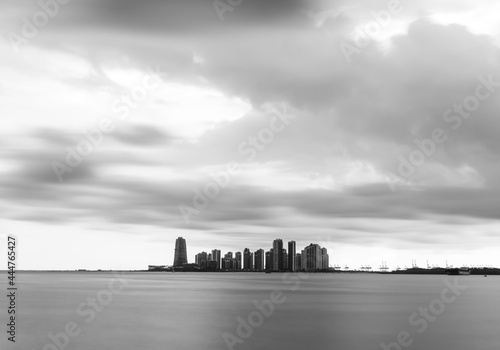 Black and white photography of a city a distant hotizon in a sea.