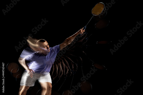 One young male badminton player, shuttler training isolated on dark background. Stroboscope effect. © master1305
