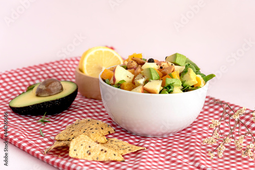 Bowl of mix fresh fruit salad on table color cloth pink background.