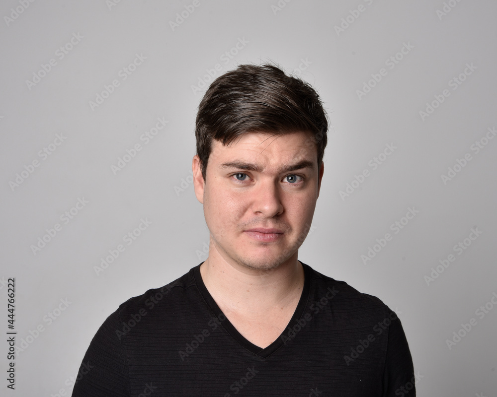 Close up head and shoulders portrait of a brunette. young man with a variety of expressive facial expressions. Isolated on a light grey studio background. Close up head and shoulders portrait of a brunette. young man with a variety of expressive facial expressions. Isolated on a light grey studio background.
